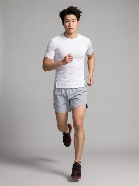 Modelo correndo, de camiseta branca e bermuda cinza