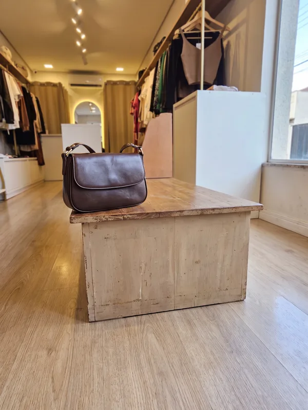 Bolsa de couro marrom sobre um banco da loja