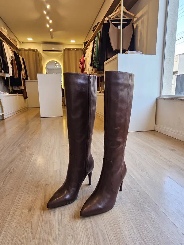 Bota de cano alto de couro marrom, no chão da loja